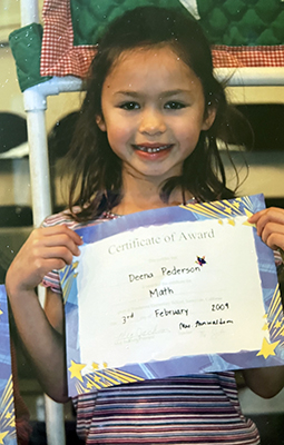 Young Deena holding a math certificate