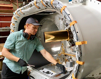 Nicholas Galitzki removes the gold-plated shield covering the telescope’s dilution refrigerator